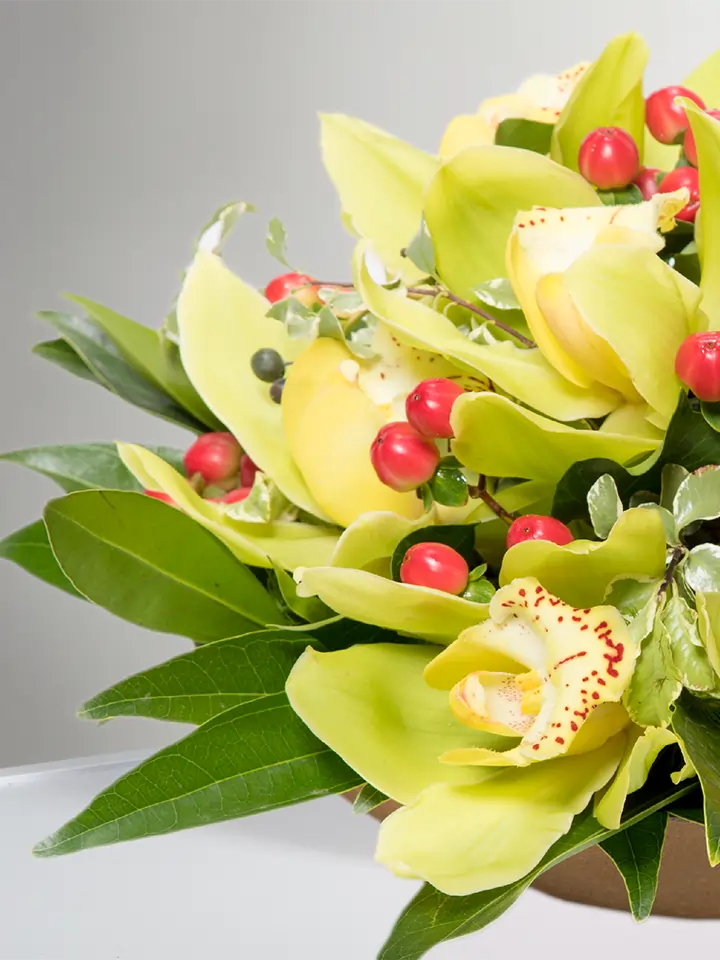 Centrotavola di fiori di cymbidium gialli e bacche rosse dettagli